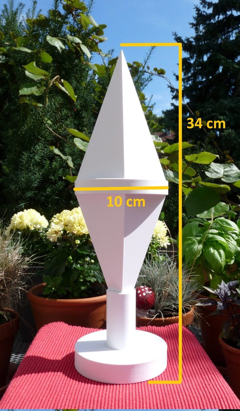 Tisch-Doppelpyramide Doppelpyramide mit eingezeichneten Größenmaßen konstruiert nach dem Goldener Schnitt auf einem Gartentisch mit blühenden Blumen.
