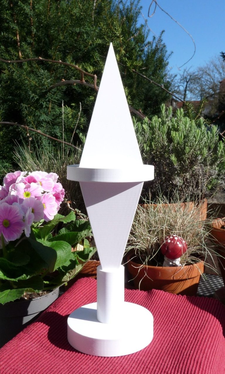 Meditationspyramide aus Kunstoff auf der Terasse stehend mit blühenden Sträuchern im Hintergrund.