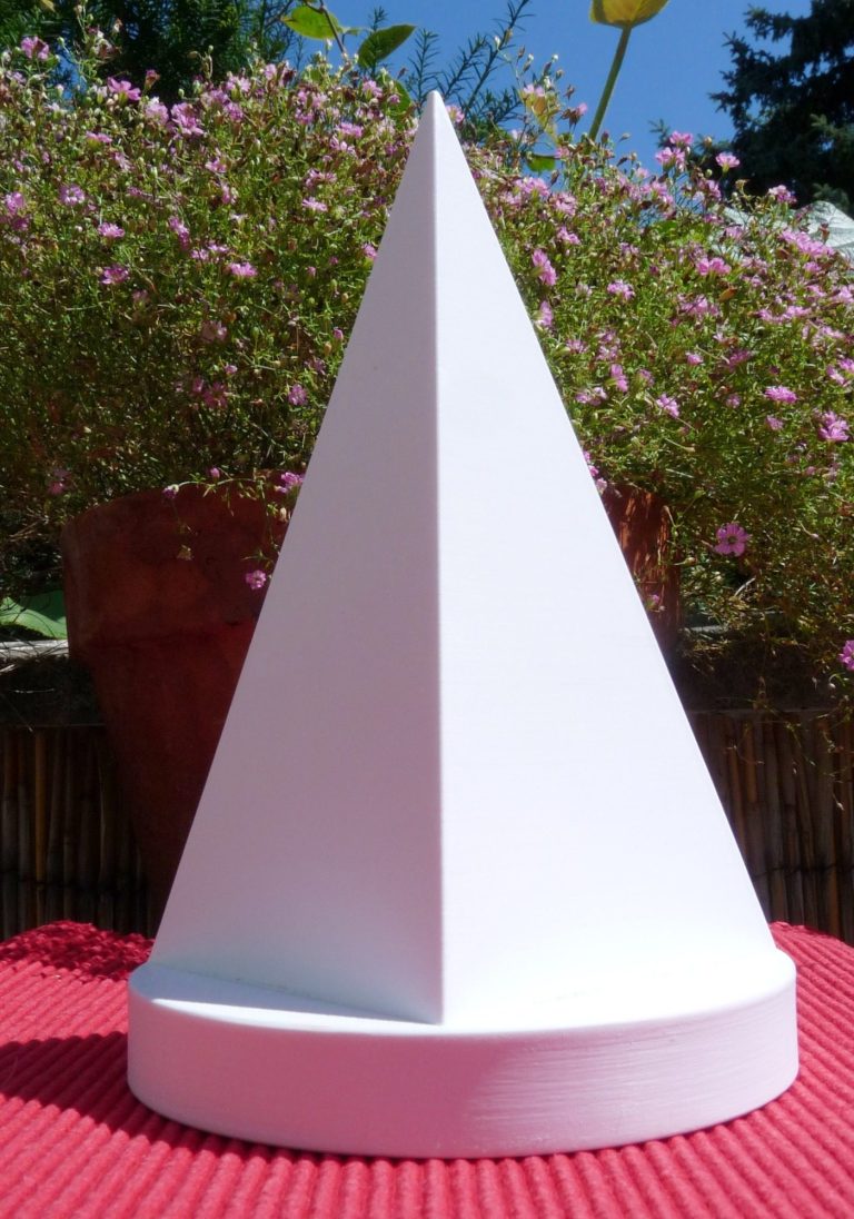 Eine Pyramide mit einem runden Podest steht auf einem Gartentisch mit blühenden Blumen.
