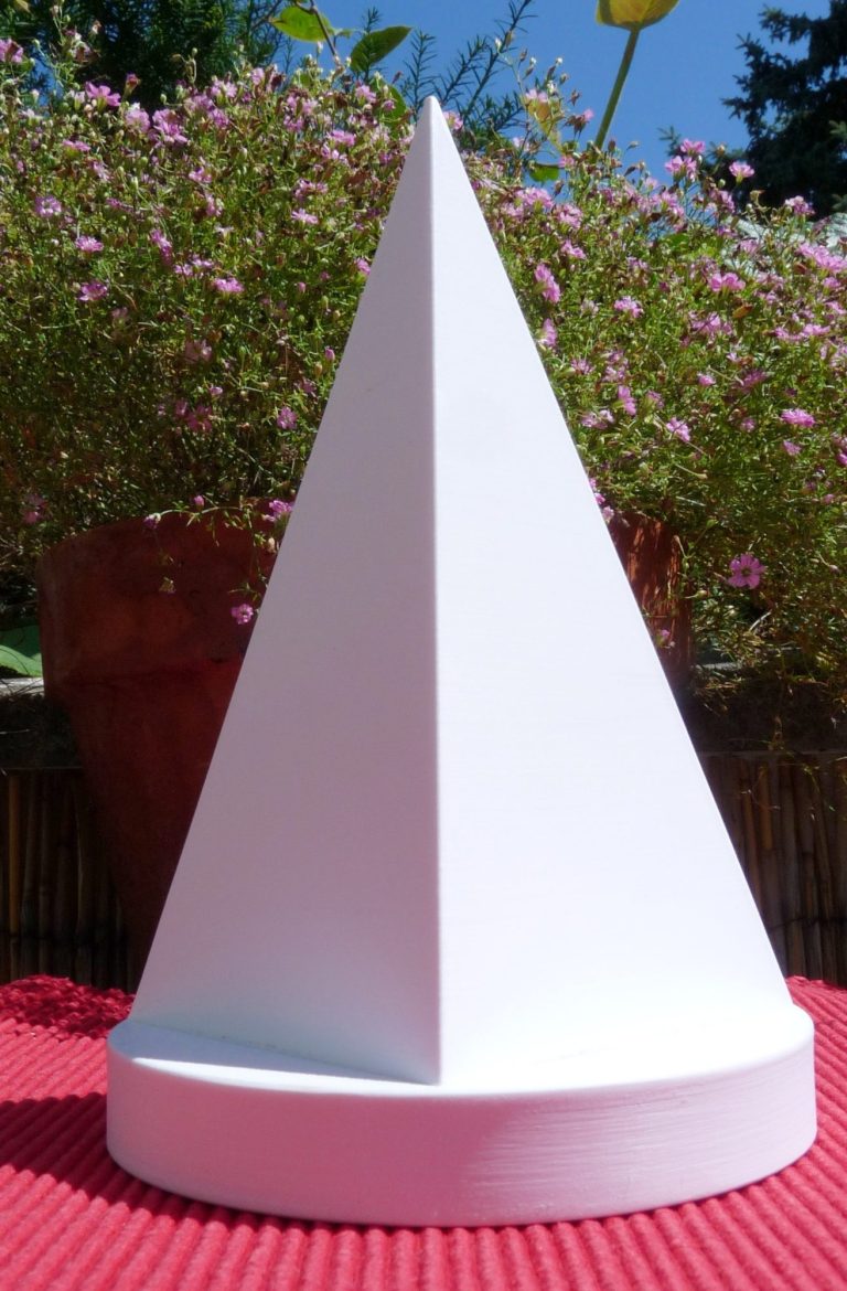 Weiße Pyramide Goldener Schnitt auf rundem Podest dahinter blühende Blumen